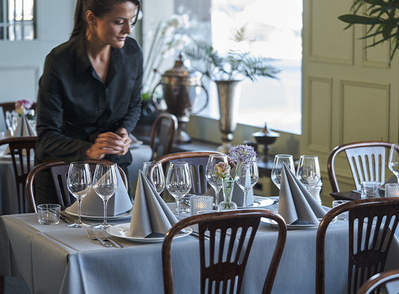 Waitress setting grey table setting in a restaurant