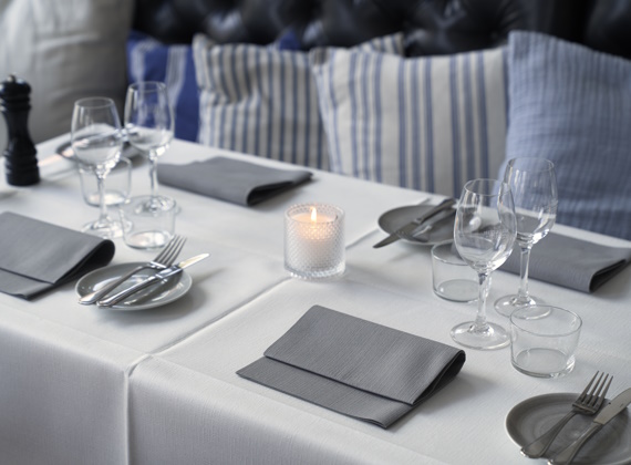 Ein Hotelrestaurant mit elegant gedeckten Tischen, geschmückt mit DUNI Tischdecken und Kerzen.jpg