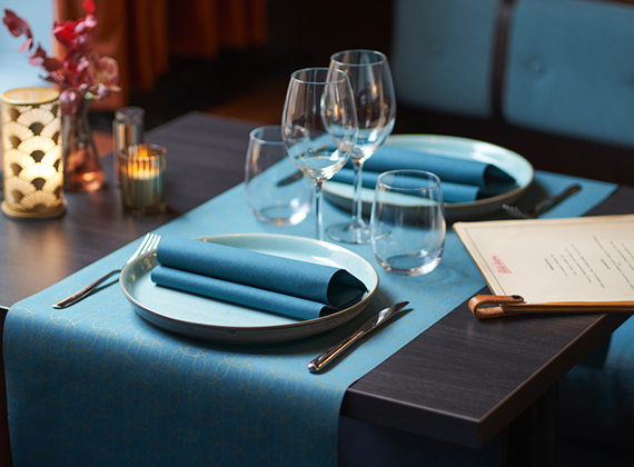 Set restaurant table with Christmas tableware - table runner and folded linen feel napkin on a plate with cutlery